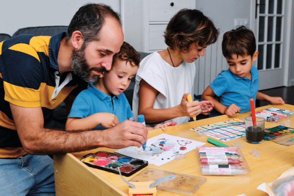 Two young boys drawing and painting with their mum and dad