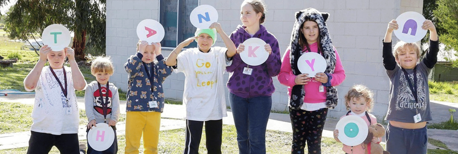Children holding letters in a sign saying "thank you"