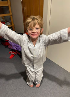 A smiling young boy waving his arms in a new pair of pyjamas