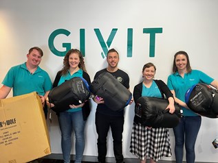 GIVIT staff holding sleeping bag donations from Black Wolf